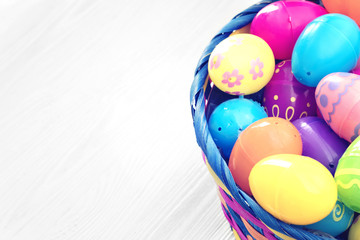 Fototapeta na wymiar Easter eggs in basket on white wooden background