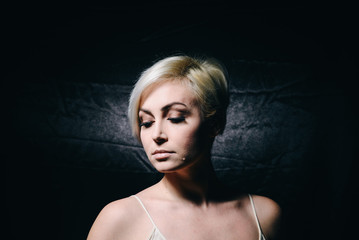 Young pretty blonde indoors on a black background
