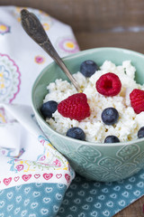 Cottage cheese in bowl with raspberries and blueberries on wooden background. Healthy breakfast .Place under the text