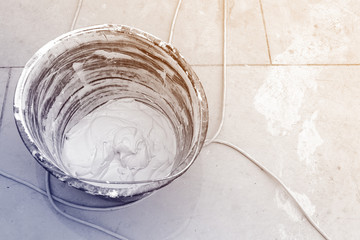 Bucket with putty ane electric wires are on the floor room of apartment is under construction,...