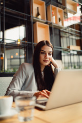 Beautiful girl working out a plan of the project and concept. Girl paints a website design on a laptop. student prints a message on the phone in the messenger. Development. Digital marketing