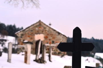 a stone church and a cross in the snow
