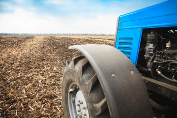 Obraz premium Old blue tractor close-up in a empty field. Agricultural machinery, field work.