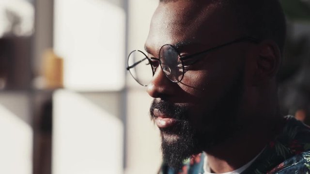 Young face african american man with glasses use laptop look at camera in sunlight job computer internet office technology working online black male holding chatting finger message close up portrait