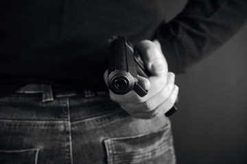 Man pointing a gun at the target on dark background, selective focus on front gun black and white photo