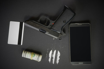 Mobile phone, powder drug like cocaine, gun, credit card and money on black table