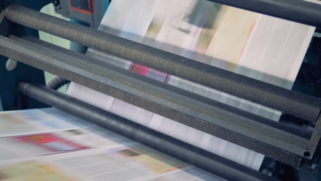 Uncut printed sheets of paper are going through typographic machine