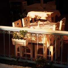 Empty wooden table with chairs in street cozy cafe lit with evening beams of the sun