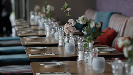 Glasses, flower fork, knife served for dinner in restaurant with cozy interior