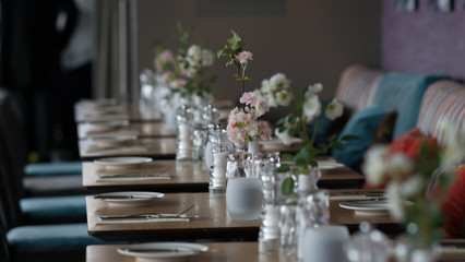 Glasses, flower fork, knife served for dinner in restaurant with cozy interior