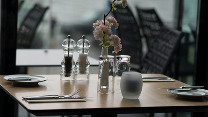 Glasses, flower fork, knife served for dinner in restaurant with cozy interior