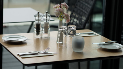 Glasses, flower fork, knife served for dinner in restaurant with cozy interior
