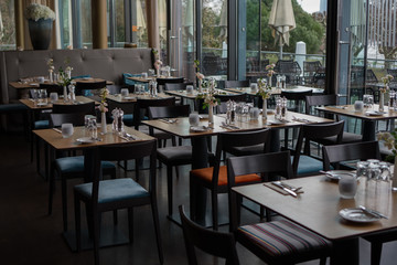 Glasses, flower fork, knife served for dinner in restaurant with cozy interior