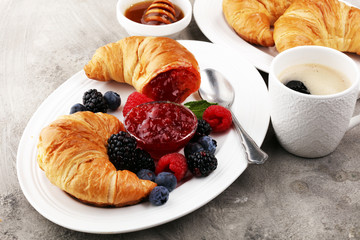 Delicious breakfast with fresh croissants and ripe berries and jam