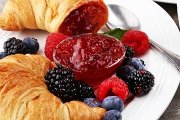 Delicious breakfast with fresh croissants and ripe berries and jam