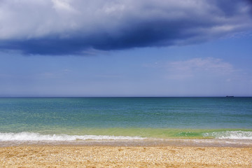 View of the seashore in sunny day and a gloomy cloud