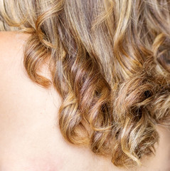 Beautiful woman's blonde and treat hair closeup, curled and back skin showing