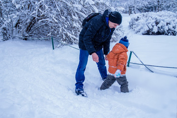 Fototapeta na wymiar Father and his son playing outside, winter forest on the background, snowing, happy and joyful