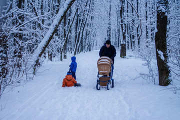 Father and children walk and play outside, winter forest on the background, snowing, happy and joyful