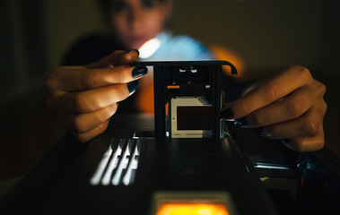 Close up of woman hands setup slide projector in the dark room