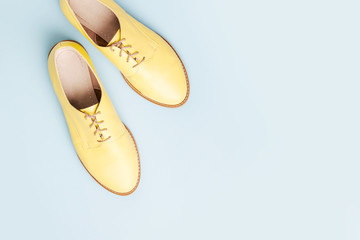 Stylish yellow shoes on pale blue background, flat lay
