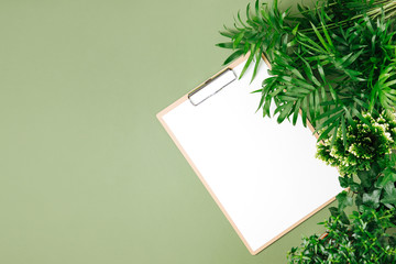 Tropical leaves and clipboard mockup  on  green  background. Top view, flat lay.