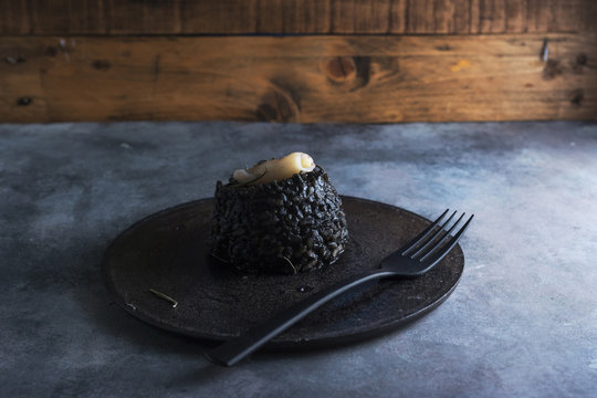 Black rice with cuttlefish, on black cement dish
