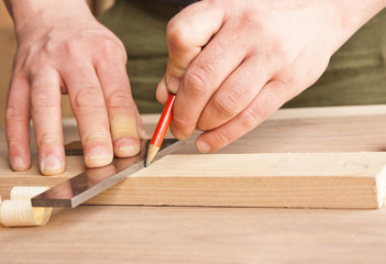 Fototapeta na wymiar carpenter makes markings in red pencil