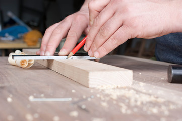 carpenter makes the marking of the wooden part in red pencil