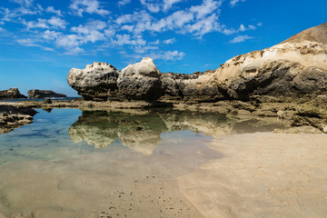 Rock formation with cliff and beach with reflections in the sea at Peterborough beach along the Great Ocean Road, Victoria, Australia