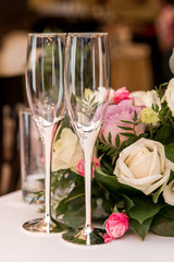 wedding glasses on the table. white and pink roses in the background. close up