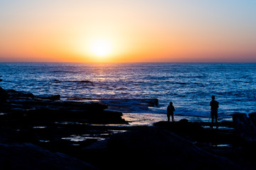 Fototapeta premium Two photographers looking out to sea on the rocks