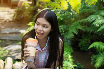 young woman is drinkink coco or coffee in the garden and relax with sunny day.