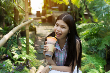young woman is drinkink coco or coffee in the garden and relax with sunny day.