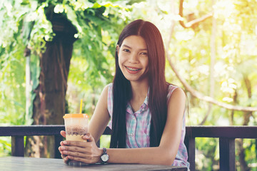 young woman is drinking coco or coffee in the garden and relax with her sunny day.
