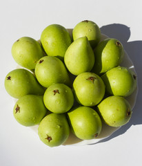 Fourteen fresh, green, pears, delicious fruit, on a white plate in the sunlight; 