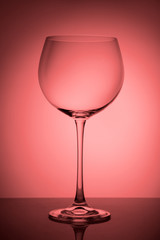 Big empty glass for red wine on pink gradient background.