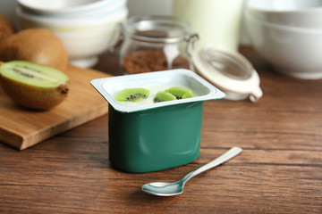 Plastic cup of yummy kiwi yogurt on wooden table