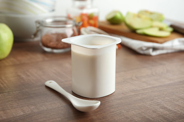 Plastic cup of yummy yogurt on wooden table