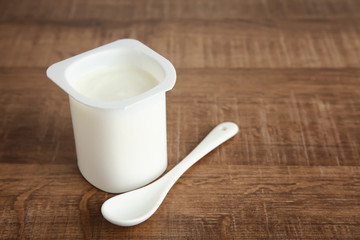 Plastic cup of yummy yogurt on wooden table