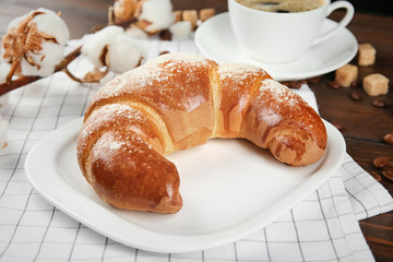 Plate with fresh tasty crescent roll on table, closeup