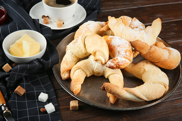 Plate with fresh tasty crescent rolls on wooden table