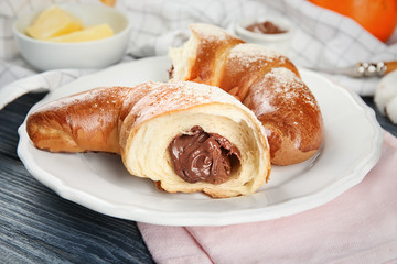 Plate with fresh tasty crescent rolls on wooden table, closeup