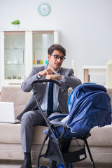 Businessman looking after newborn baby at home and teleworking