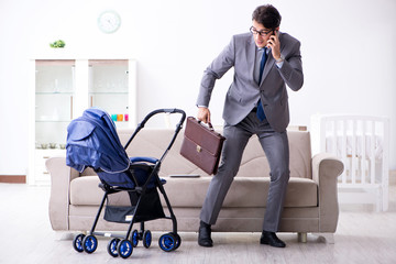 Businessman looking after newborn baby at home and teleworking