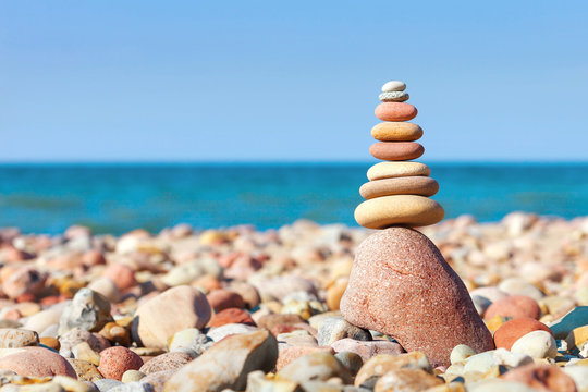 Pyramid of colored pebbles on a background of the summer sea. Concept of harmony, balance and meditation.