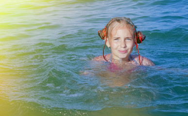Vacations at sea. Portrait of young beautiful girl swimming in the transparent sea. (Holiday, rest, travel, childhood concept)