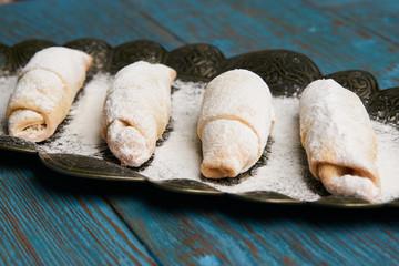 Mutaki cookies rolled with powdered sugar on copper tray on rustic wooden table, turkish food 