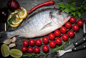 Fresh Dorado fish with spices and vegetables on slate plate