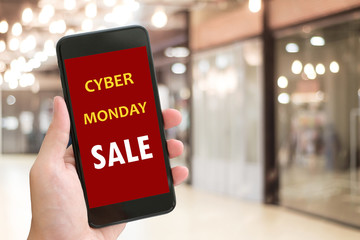 Hand using smart phone with cyber monday sale on screen device over blur background with copy space, business technology and lifestyle concept